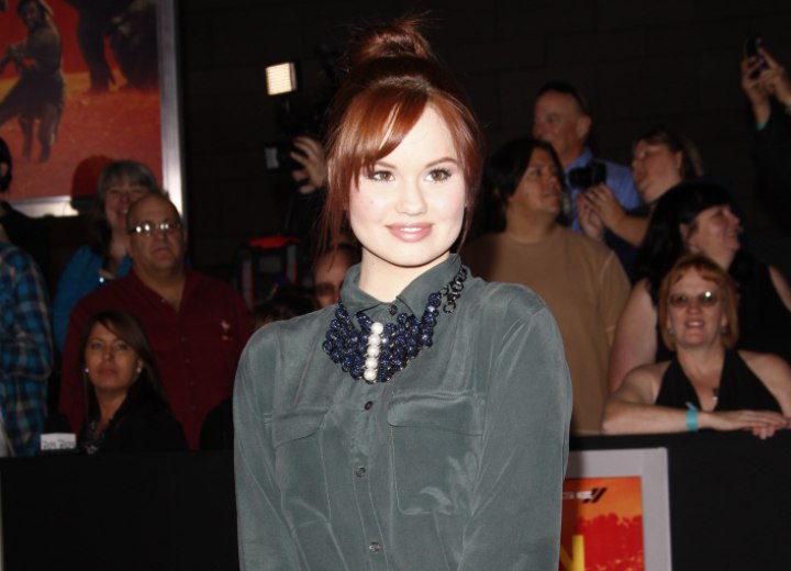 Debby Ryan  Flirty top knot hairstyle and a buttoned-up silk shirt